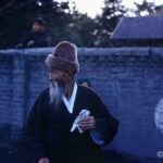 IslBG An elder in traditional dress in front of a school